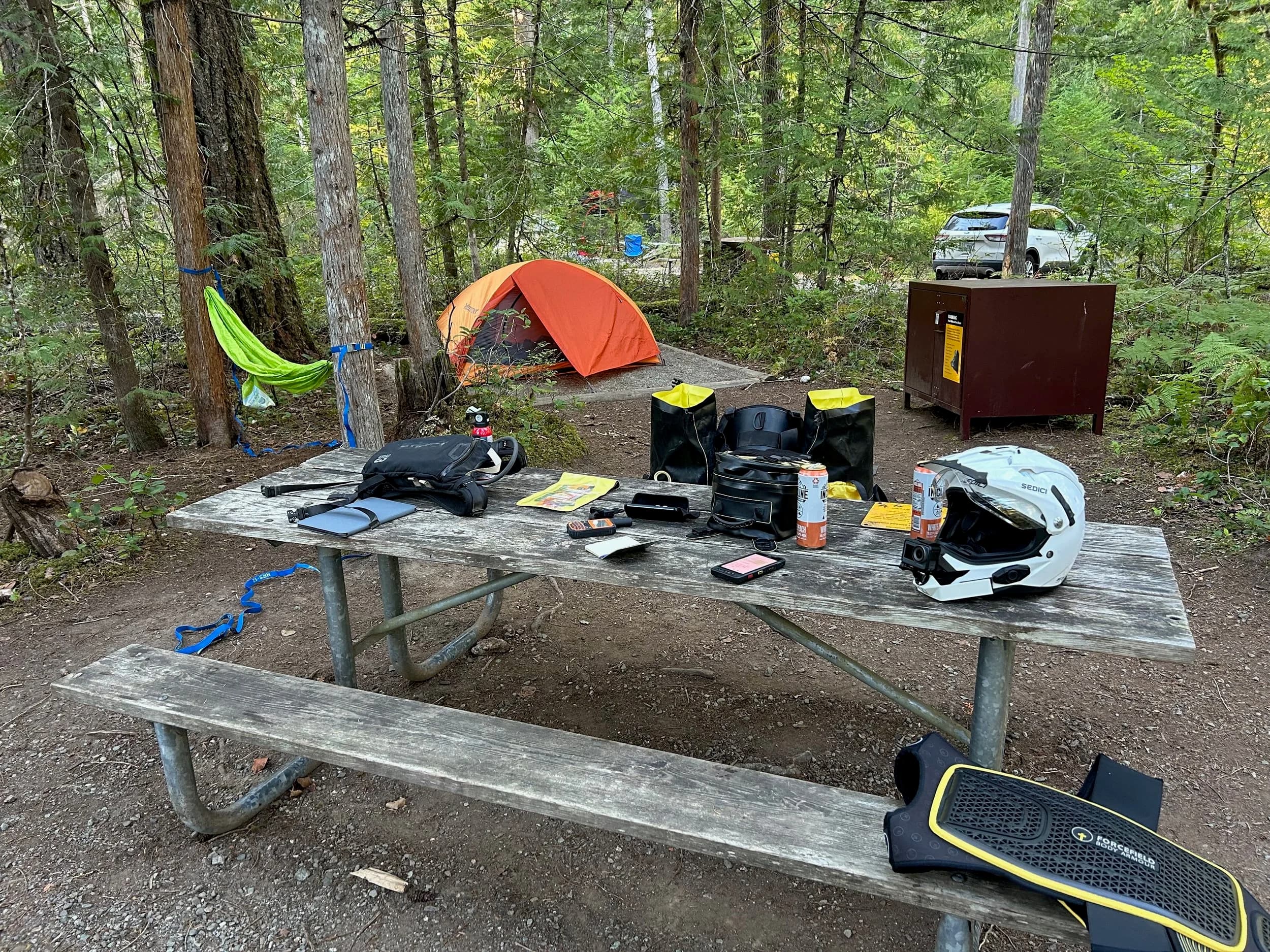 Trip Report: NW National Parks Loop
I left my job recently to take a much needed sabbatical and figure out what I’m doing next. A few weeks after my last day at work I embarked on what was to be a three week tour of NW-ish National Parks from Portland, to include Olympic, North Cascades, Glacier, Yellowstone, Grand Teton, Craters of the Moon, Lassen Volcanic, and Crater Lake.
I ended up missing Grand Tetons due to weather and I had to cut the trip short before I got to Lassen (family medical issue), so Lassen and Crater Lake remain unvisited.
Trip Dates: Sept 3 - Sept 16 (13 days)
Total Travel Miles: 3478 (does not include local miles for store runs, etc.)
Total Gallons of Gas Used: 82
Equipment: 2021 Benelli TRK502X Gaia GPS & Google Maps running on Sonim XP8 rugged Android phoneButler Motorcycle Maps (paper maps of best M/C roads in the country) iPhone 14 (main camera) Akaso Brave 7 helmet-mounted adventure camera Spot X satellite communicator and tracker Wolfman Luggage WP waterproof tank bag and saddle bags (no longer available) Watershed Colorado dry bag duffel (across the pillion seat) Kriega US-5 Drypack (tail bag) Kriega 3L hydration backpack (strapped to duffel, not worn)Marmot Ajax 2 tent Nemo hydrophobic down sleeping bag (non-mummy)Helinox ultralight cot MSR WhisperLite International stove
(Purchased in 1991 for my first moto trip: Detroit, MI to San Diego and back on an XT250)Gossamer Gear Bare Boxer bear-proof food canisters (two - one in each saddle bag)
Day 1 - Olympic National Park Date: Tuesday 9/3/2024
Destination: South Beach Campground, Olympic National Park
Travel Time: 4h 24m
Miles: 213Notes:
Planned to head west to Astoria then north from there, but left later than expected so headed up I-5 to US 12. I’ve driven/ridden that stretch of I-5 hundreds of times (starting in 1993). It’s boring and I hate it.
South Beach CG is first-come-first-served. I didn’t have issue getting a site. There is a long, tight loop of sites along the coastline, but I chose one of the sites further back near the bathrooms due to wind concerns. The bathroom building provided a sort of wind shelter for my site.
I used the heated grips on this leg; it was pretty chilly along the coast in the Olympic Peninsula. I almost didn’t install them, thinking I was being paranoid about the cold. I ended up using them a lot.
Day 2 - Ferry to Seattle / Burien Date: Wednesday 9/4/2024
Destination: Friend’s house in Burien, WA
Travel Time: 7h 30m
Miles: 199
Notes:
Slept well (thanks to Advil PM). I’ve not been sleeping well for more than a year. I’m really hoping to reset my sleep patterns with this trip. A good night’s sleep is one of my great joys and I feel like I’ve been robbed of that pleasure.
Used my Aeropress this morning for the first time ever. I’m hooked.
Headed up along US 101 through Port Angeles and then down to the Southworth ferry terminal near Port Orchard. Ferried across to Fauntleroy, which is just a few miles north my friend’s house in Burien. I’m always surprised at how long it takes to get from the Olympic Peninsula to the east side of Puget Sound (Seattle, etc.). With the ferry crossing (I love ferries) it took seven and a half hours to go 200 miles.
Discovered at my first stop of the day (just up 101 at the Kalaloch Campground, stopped to refill water) that the battery is quite weak and won’t start the bike if you leave the ignition on for even two minutes without the motor running. This would become a theme for the next few days. Fortunately, I have a jumper box and a permanent jump harness wired to the battery so jump starts are a quick operation.
Had a good evening with old friends.
Day 3 - North Cascades via Mountain Loop RoadDate: Thursday 9/5/2024
Destination: Newhalem Campground, North Cascades National Park
Travel Time: 4h 30m
Miles: 146Notes:
Slept well, on the couch. No pills needed.
I realized yesterday that my summer riding gloves (Rev’It Dune) were a size (or two) too small. Rev’It gloves fit really tight and I feel like I can never get it quite right. And yet, I love them. So, I stopped at a Cycle Gear in Bellevue to pick up something summer weight (Dirt 3) that fit better. They’re better, but maybe still one size too small. Such is life.
From Bellevue, I rode north and took the Mountain Loop Hwy then on up north to North Cascades. It was a hot ride. Still summer.
A small section of the Mountain Loop Road is dirt/gravel, which I didn’t realize. No biggie. Was just surprised (clearly I didn’t study my maps closely enough). When riding solo on a bike that weighs over 500 lbs., I tend to avoid planning much off-pavement riding. That’s what my DR-Z is for.
Day 4 - Newport, Washington via Winthrop Date: Friday 9/6/2024
Destination: Golden Spur Motor Inn, Newport, Washington
Travel Time: 8h
Miles: 308
Notes:
Slept just ok, even with Advil PM.
Pretty ride through North Cascades National Park and Colville National Forest. Didn’t do any backroads or hikes. Discovered (new to me) the town of Winthrop. Stopped for coffee at Sheri’s and resupplied on freeze-dried food at Cascades Outdoor Store.
The town of Newport is almost nothing, but, inexplicably, there’s an amazing restaurant (Brownell’s Place). Had dinner and a few ciders. Met and chatted with the owner/chef (she’s great). Listened to some live music. Then back to the motel.
Day 5 - New Battery in Kalispell Date: Saturday 9/7/2024
Destination: West Glacier KOA, West Glacier, MT
Travel Time: 8h 7m
Miles: 293
Notes:
Slept well on motel bed (on sleeping bag, not in the sheets). Another hot one.
Discovered that the water pump seal leaks oil. A quick post in the TRK Facebook group revealed that this is a common problem on this bike, and and easy fix. It’s apparently just a bad o-ring.
Battery has been getting continuously worse, and now requires I jump start the bike about every other start. Google Maps to the rescue: directions to the Batteries Plus in Kalispell, please. They don’t have an Odyssey AGM in the right size; the Duracell will have to do. (It’s been great.)
I set up camp at the West Glacier KOA, which will be my base for a few days. KOAs are their own little world. Very strange. Not really my thing, but the on-site laundry was handy.
After setting up camp I opened a cider and used the iPad to book a vehicle reservation for the next day to ride Going to the Sun Road, which I really wanted to do.
Day 6 - Going to the Sun RoadDate: Sunday 9/8/2024
Destination: Local Ride: West Glacier, Going to the Sun Road, Saint Mary, East Glacier
Travel Time: 5h 35m
Miles: 142Notes:
Quick breakfast and gas up in West Glacier before entering Going to the Sun Road.
Going to the Sun Road was stunning. This was the first point in the trip where I had tingles and was giddy at what I was seeing.
Took a very short hike along Saint Mary Lake. Again, I was beside myself with the beauty.
Lunch at the general store in Kiowa.
The rest of the ride back after East Glacier was meh, but I just kept thinking about how amazing what I’d seen in the morning had been.
Dinner at the KOA. Tacos from a cart (ok / not great, and a very weird guacamole) and a few glasses of wine from another cart. I asked about the guac and it turns out they make it in a food processor. Come on, people.
Day 7 - Ride to BozemanDate: Monday 9/9/2024
Destination: Friend’s house in Bozeman, Montana
Travel Time: ~ 8h (Gaia crashed near the end of the trip, but before getting to Bozeman)
Miles: ~ 400Notes:
Slept poorly again. No pills this time. Took some photos of my soft luggage setup to answer some questions in the TRK502X Facebook group. The saddle bags are from Wolfman Luggage, but I don’t think they make this waterproof line anymore. I use a duffel dry bag from Watershed across the top. A heat shield protects the side bag from exhaust heat.
Hazy, smoky ride most of the way. Very windy in places. This is where I first really started to feel how underpowered the TRK502 is. Really struggled in places.
Developed an engine-speed-sensitive squeak or rattle. Sounds like when a heat shield vibrates in resonance with engine vibration. Discovered that it’s a missing crash bar mounting bolt allowing the crash bar to rub against the frame.
Also noticed that there’s a resonant oscillation at speed that feels like the chain going bad (like it’s stretching unevenly).
First of several nights at a friend’s house in Bozeman (which, it turns out, is a pretty cool town). And there’s a hot tub…
Day 8 - Bike Maintenance & Hyalite ReservoirDate: Tuesday 9/10/2024
Destination: Local Ride: Hyalite Reservoir
Travel Time: not recorded
Miles: not recordedNotes:
Woke up to a smoky sunrise. I had the best night’s sleep I’ve had in years. This is was the whole point of this trip: to untangle my burnout and reclaim sleep as one of my joys. I wrote about it in my journal when I woke up. I hope this wasn’t a fluke.
Planned to replace the bolt that rattled loose from the crash bar, but instead discovered that it had actually severed off at the mount point. No fixing that on the road. Adjusted chain and moved on.
Lunch at Mountains Walking Brewery in Bozeman.
Rode up to Hyalite Reservoir. Pretty ride. Smoky still.
Soaked in hot tub after dinner.
Day 9 - North Yellowstone LoopDate: Wednesday 9/11/2024
Destination: Northern loop through Yellowstone National Park
Travel Time: 9h 36m
Miles: 272Notes:
Did a day trip from Bozeman down through the northern loop in Yellowstone, entering at Mammoth and taking the scenic route through Paradise Valley.
Saw elk, coyotes (I think), buffalo, and pronghorn.
Pretty ride, but cold in places. Used heated grips again.
Rode the loop through Mammoth Hot Springs (see video) at the end.
Coffee at Tumbleweed Bookstore & Cafe in Gardiner. I kind of dig Gardiner. Good vibe.
Had dinner at Mountains Walking Brewing. Rain and wind started. Lights flickered. Waited for rain to stop before riding back to the house.
Power out at the house due to high winds. This does not bode well for tomorrow.
Day 10 - Winter Weather in the ParksDate: Thursday 9/12/2024
Destination: Grand Teton National Park via West Yellowstone Pocatello, Idaho
Travel Time: 5h 40m
Miles: 201Notes:
Today was supposed to be a gorgeous ride through Yellowstone into Grand Teton National Park, and camping at Signal Mountain CG in the park. The weather had other ideas. It was pouring rain (and cold) all the way to West Yellowstone from Bozeman. By the time I got to West Yellowstone I was getting severe winter weather warnings on my phone calling for up to 3 (three!!) inches of snow accumulating in the high passes in the park. It’s bad enough in a car, but that’s a disaster waiting to happen on a motorcycle.
I parked my butt at Mountain Mama’s Cafe in West Yellowstone to warm up / dry off and decide what to do. I almost had myself convinced to push through when I realized that, even if I made it to the campground ok, I’d be setting up camp in the rain and I’d likely be miserable all night. Grand Teton would have to wait.
From West Yellowstone it’s easy to bail west into Idaho and get away from the park weather and elevations. So that’s what I did. It was not a pleasant ride, though. I was in torrential downpours all the way to Idaho Falls.
Arriving in Idaho Falls, I was exhausted and sure I could just find a room for the night. I dropped the bike at a roundabout (short-legged it coming to a stop; I knew it was going so I just rolled away). Guy behind me helped me pick it up. Then, there were no rooms because it was move in week for the two universities there (U of I, ISU). This would become a recurring theme.
I rode further to Blackfoot. Still no rooms.
I called ahead to Pocatello and got a room at a Red Lion there. I was never so happy to be off the bike.
No pictures this day. I couldn’t even get the action camera to turn on.
Day 11 - Craters of the Moon and EBR-1Date: Friday 9/13/2024
Destination: Craters of the Moon National Monument
Travel Time: 4h 20m
Miles: 124
Notes:
I wasn’t sure what my destination would be today but my plan was to do a little nuclear tourism, see Craters of the Moon, and then go somewhere from there. My schedule and day-plan was thrown off by missing Grand Teton National Park and spending a night in Pocatello, which was not on the itinerary at all.
Stopped in Atomic City. Not sure why; I was under the impression that Atomic City was the first city lit by nuclear engergy, but it was practically a ghost town. There are a few houses there, but as far as I could tell all of the business were shuttered. Except, maybe, for the race track; that looked like it might still get used.
Arco, it turns out, is the city celebrated as the first in the world to be lit by nuclear energy. Nothing special about the town, but they do a nice job of making City Hall photo-worthy.
Between Atomic City and Arco is EBR-1 (Experimental Breeder Reactor I) which was the world’s first breeder reactor. The EBR-1 exhibit was closed for the season, but in the lot next to it were some really interesting experimental nuclear heat-transfer jet engines that never made it out of the experimental phase (probably a good thing).
Craters of the Moon is pretty small. If you don’t do any of the walks, it’s literally just a 30 minute road loop. Still, it was an unexpected surprise and delight. I had no idea what to expect but I was positively chuffed at the experience. I noticed that the campground had open sites so I inquired at the entry booth. As luck would have it, the whole campground is first come / first serve. I decided to set up for the night. It’s good to be done early and have some time to read and not stress about making distance.
Day 12 - New Chain in Twin FallsDate: Saturday 9/14/2024
Destination: Battle Mountain, Nevada
Travel Time: 8h 52m
Miles: 335
Notes:
Beautiful morning in Craters of the Moon. While I was breaking camp a parade of classic cars came into the park to drive the loop. I got a picture of one Pontiac down the road in Carey at a gas station.
Carey ended up being an unplanned fork in the road for me. I discovered this morning that my chain was indeed stretching unevenly, and the oscillation I was feeling and hearing was the chain hum changing from a “loose” hum to a “tight” hum rapidly as the tight spot moved around the sprockets. I was supposed to continue west to Mountain Home and then south from there into Nevada. A very scenic route, according to my Butler map. But, between camp and the gas station I got pretty paranoid about the chain snapping at high speed, which, worst case, could lead to a fatal crash.
So I called ahead to a few motorcycle dealers in Mountain Home (on my planned route) to see if they could take me in and replace the chain. No dice. This is the downside of having an obscure motorcycle from an obscure marque - no one wants to work on it. Making matters worse this is an Italian-designed bike built in China, a fact which causes many people to lose the ability to think clearly. “It’s Chinese junk!” Not so. Next.
With Mountain Home out, I tried Twin Falls. My first call was to Adventure Motorsports, and the service manager there took me in with no hesitation. “How soon can you be here?” I didn’t get his name, but my hat’s off to him and his one tech working furiously on a Saturday to beat the 3pm closing time. He said during high season, they get about 15-20 out of town travelers per week who need something done, and they take them all in. I love to hear stuff like this. This shop is in it for the community. They have a nice showroom, too.
With a quality new chain installed, I got a burrito and a MexiCoke at a Mexican place and went on my way. I made it to Battle Mountain, NV, where I decide to get a room. Tomorrow I rejoin my planned scenic route. Day 13 - Desert Mountains in NV, CADate: Sunday 9/15/2024
Destination: Grizzly Campground, Lake Davis (near Portola, CA)
Travel Time: 7h
Miles: 307
Notes:
I love the northern Nevada landscape, and today’s ride didn’t disappoint. US Highway 50 is apparently known as “The Loneliest Highway” but everyone knows about it, so it’s not very lonely. However, after leaving Austin, NV headed west you can take Nevada Highway 722, which dips to the south and follows the old US 50 route. It was completely empty and the twisties through the passes were fun. Highly recommended.
Stopped in Fallon for gas and to find a Micro SD card for the action camera. Walmart to the rescue.
After Reno, I crossed into California and, I swear, it looks different. Norther California desert mountains are so beautiful.
Camped at a nearly empty campground on Lake Davis (very end of the season). The host warned me rain was coming tomorrow.
Day 14 - Unplanned Return HomeDate: Monday 9/16/2024
Destination: Summit Lake Campground, Lassen Volcanic National Park Portland, Oregon (Home)
Travel Time: 10h 32m
Miles: 538Notes:
Last week, my mom went into the hospital for a fairly routine procedure. My brother went to Michigan to help out, as needed, and he went back home to Arizona after she returned home and everything seemed settled.
This morning, while having coffee, I got a call that she’d gone back into the hospital with something that may or may not have been related to the procedure. It seemed like maybe things were ok, but maybe not.
I decided the best thing to do was head home so that I was near an airport if I needed to fly out to Michigan to help out.
I packed up camp and headed up US 395 toward home, via Klamath Falls. It was a pretty ride, but, once again, I found myself in rain most of the way to Klamath Falls.
I was pretty beat by the time I got to Klamath Falls and figured I’d just find a hotel room, get a hot shower, and finish the ride tomorrow.
But, once again, it was move-in week for the local university. Holiday Inn Express had a single room for $395. No thanks. Onward.
I never hit rain again after Klamath Falls, and after turning west onto Oregon Hwy 58 and starting to lose elevation into the Willamette Valley, the temperature starting rising, which was welcome.
Once I reached Eugene, there was no point in not just going all the way home, so that’s what I did.
I got two pictures: one at camp before the call, and one at my last gas stop, an hour and twenty minutes from home, with the moon rising.
A nice side effect of my early return home is that I was home for my birthday (tomorrow), so I had dinner with my kids and my wife, which was lovely.
I did end up flying to Michigan the next day, and was there for a bit. The best part? I got to make some meals for my mom and step dad. Everything seems ok with my mom for now.
Grand Teton, Lassen, and Crater Lake will be there, and now I have an excuse for another trip in the future.