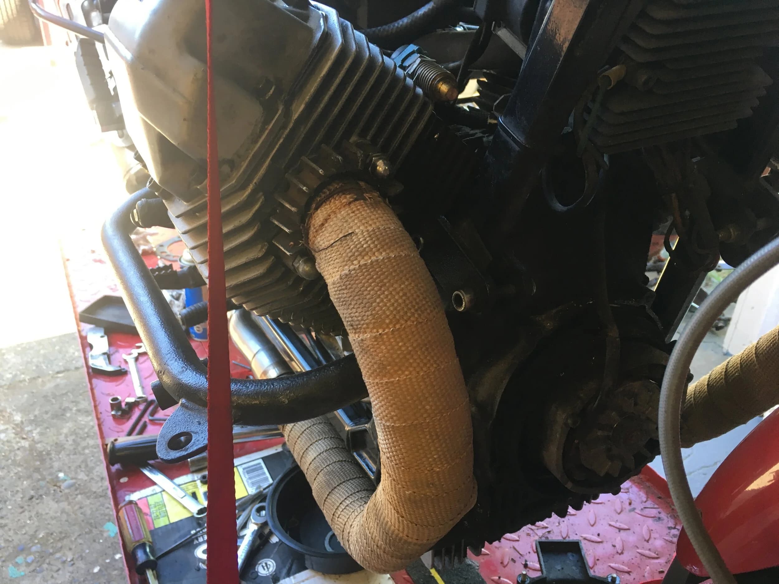 State of the Quota, pt. One
If you’ve read my first post or the About section, you know I’m planning on riding a Moto Guzzi Quota 1100ES on the first several sections of the Nevada BDR (along with my brother on his KLR 650) in spring 2020. There’s a lot of prep to do before then, but let’s start with the State of the Quota.
The bike in question was made in Mandello del Lario, Italy at the historic Moto Guzzi factory. Moto Guzzi, established in 1921, is the oldest European motorcycle works in continuous production. The Quota 1100ES was made from 1998 to 2001 but was only sent to the United States, in very small quantities, for the 1999 and 2000 model years. I can’t find a definitive source, but the consensus seems to be that only about 130 units total were sent to the US. The one I own is model year 2000 and is the only one I’ve ever seen in real life. It’s probably a safe bet that only half of those original US-bound bikes are still on the road. It’s a very small club.
The good news, though, is that, although the frame and body components are entirely unique, the motor and drivetrain are assembled from common Guzzi parts and are easy to come by. That said, it would really be smart to buy a second Quota as a parts donor bike. Some things, like shift levers and body parts, are getting harder to find (and much more expensive). The club is getting smaller.
I acquired my Quota in the spring of 2018 from my buddy Patrick in Seattle who collects, builds and barters all things Moto Guzzi. I’m not sure how or why he had it. He’s not an “adventure” rider. I think he just thought it was cool. Which it is.
The bike needed a bit of work when I bought it and part of the deal was that we’d do that work together, in his garage, before I trailered it back home to Portland. So, over the course of a weekend, we replaced a head that had a stripped out exhaust stud with a spare Patrick had laying around (see note above about collecting and bartering), swapped out the middle muffler for straight-through Y-pipe, changed the fluids, and adjusted the valves.
Sounds all very simple, but there was a hiccup. After installing the replacement head and moving on to reassembly and connection of the accessory components we discovered that there was no place in the new head for the head temp sensor, which is used by the electronic fuel injection (EFI) system. In the original head, there’s a threaded bore into which the threaded end of the brass sensor unit is screwed. No such bore on the donor head.
After some calling around to Patrick’s Moto Guzzi mechanic friends, it was decided that the brass heat sink of the temp sensor simply needs to be in contact with the head somewhere and that would provide enough thermal transfer to give the EFI the engine temp info it needs to adjust fuel delivery properly. So, Patrick drilled some small holes into the cooling fins on the inboard side of the head and lashed the temp sensor assembly to the head sideways, brass to aluminum. It seems to work. It’s been working for two years. All the same it’s not like me to jury-rig something like this, and it bugs me constantly. Even more so now that I’ve admitted my mechanical transgression publicly.
You’ll note in a later post that I have stainless safety wire on my packing list…and you’ll know why.
With that out of the way, here’s a catalog of what’s been done to date and the current state of the Quota. Mods & Repairs To Date Electrical Battery (upgraded to Odyssey AGM) Stator (replaced failing unit)Regulator / Rectifier (retrofit a Drag Specialties Harley Davidson part less finicky about AGM batteries) Headlight (retrofit an MZ Skorpion head - the original is dangerously anemic) Riding / “see me” lights (added)Voltage meter (added to dash) Mechanical Right-side head (replaced with donor)Head temp sensor (bastardized, see above) Middle muffler (replaced with Mistral Y-pipe)Front crank seal (replaced) Exhaust crossover removed, headers wrapped (done by previous owner, these always crack) Running Gear Rear wheel rim (replaced with Sun Rims wheel from a wrecked Quota, found on eBay; the original Excel rears are crack-prone)Tires (Avon Trekriders 50/50 adventure sport)Pinned shift actuator lever to shaft (it kept falling off while I was riding!)AccessoriesUSB charge portPhone mount (Perfect Squeeze from Hondo Garage)Tool tube (from Agri Supply)Barkbusters Heated grips (added by previous owner)
The bike also has OEM Hepco+Becker Moto Guzzi hard bags which, in my opinion, are really made for road travel. I’m considering whether to use them on Nevada BDR trip. Leaning toward no; the mounting hardware makes a good platform for soft luggage, though.
Next post we’ll look at the to-do and wish lists heading into Nevada.